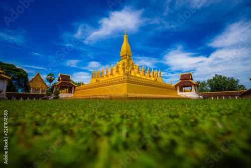 Golden pha that luang buddhist stupa with blue sky and green