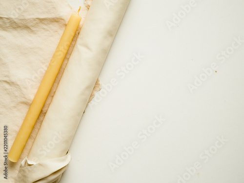 Unlit beeswax taper beside an unrolled blank paper scroll, concept of a fresh start and unwritten future
