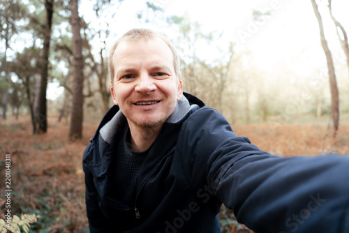 Man smiling taking selfie while spending time in forest