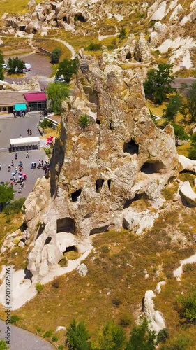 Vertical video. Goreme, Nevsehir, Turkey. Monastery of Nuns and Monks rock-cut complex, towering fairy chimney with carved openings, aerial drone view over the UNESCO World Heritage landscape of Capp