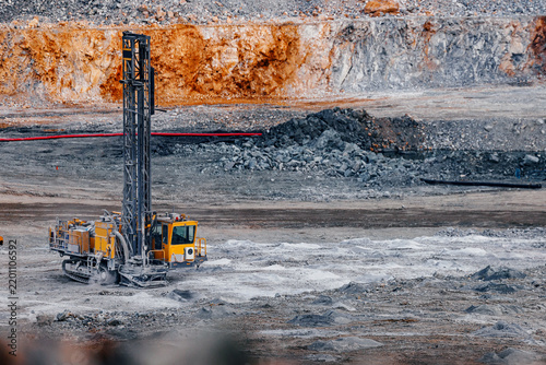 Drilling rig operating in open pit mine with rocky benches for mineral exploration and industrial site background