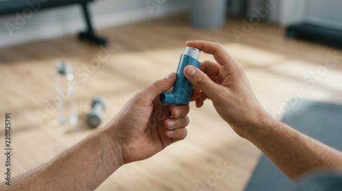 Man's hands holding an asthma inhaler in a home gym setting, with dumbbells and water bottle blurred in background.