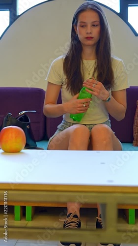 Young woman opening a plastic water bottle while relaxing indoors
