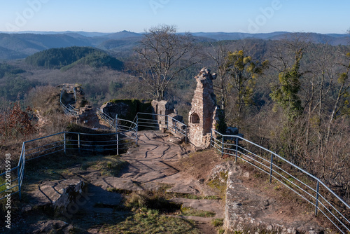 Passerelle et escalier métallique menant aux ruines d'un château médiéval au sommet d'un éperon rocheux, avec panorama sur les forêts environnantes (château du Falkenstein, France)