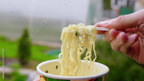 Man eating instant egg noodles outdoors