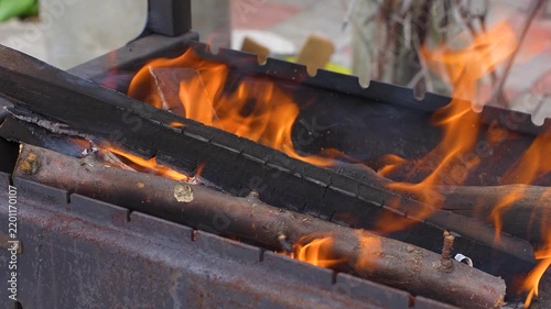 Bright orange flames and glowing embers burning inside a metal charcoal grill (mangal).