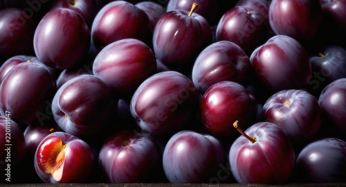 Fresh purple plum fruits on dark wooden table.