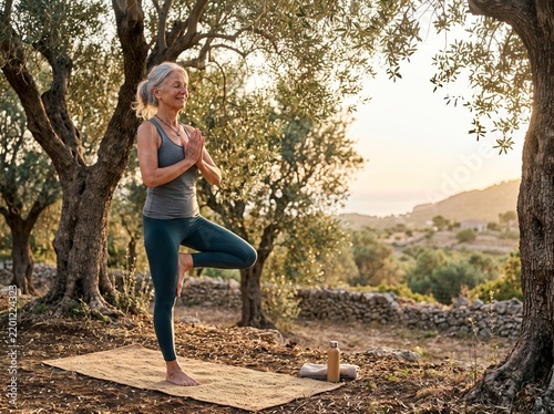 Senior Woman Practicing Yoga Outdoors Beneath Olive Trees at Sunrise