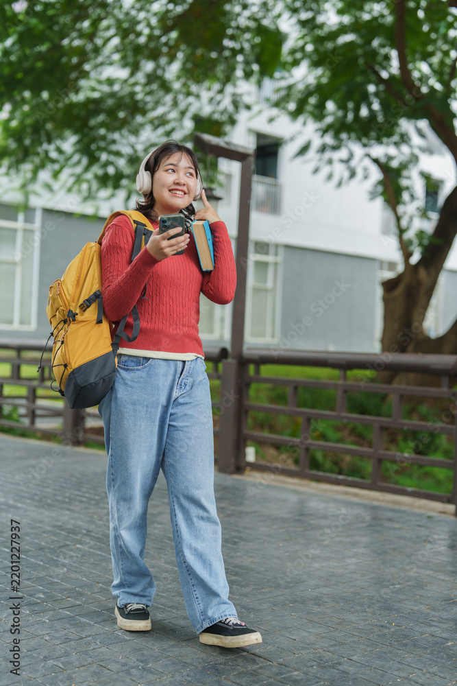 Obraz premium Female student walking on campus listening music