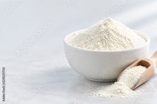 White ceramic bowl of fine ivory powder with wooden scoop, natural ingredient and beauty product concept