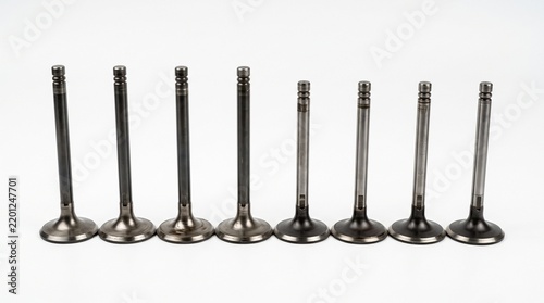 Set of polished chrome engine valves arranged in row against clean white background