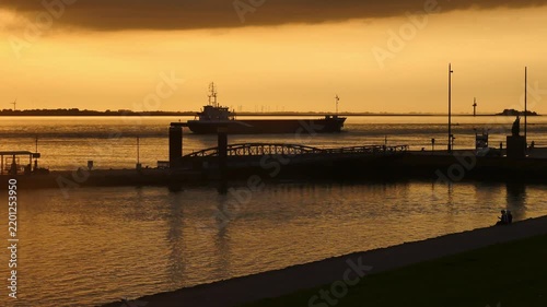 15.09.2026, Bremerhaven - Lower Saxony - Germany. Sunset over the river Weser with a ship heading to the harbour.
