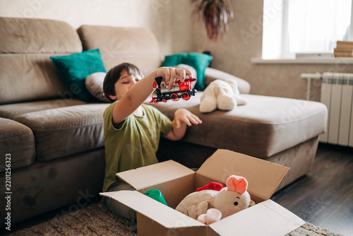 Happy cheerful kid boy packing his toys for delivery donation box. Charity and recycling