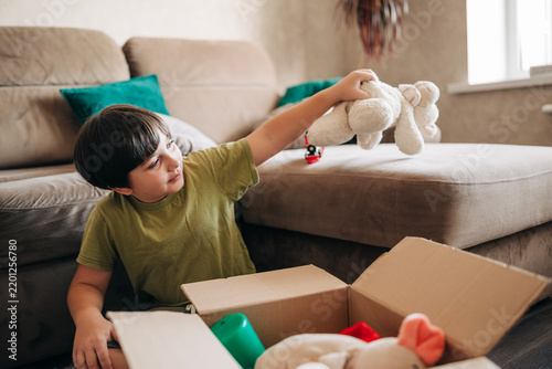 Happy cheerful kid boy packing his toys for delivery donation box. Charity and recycling