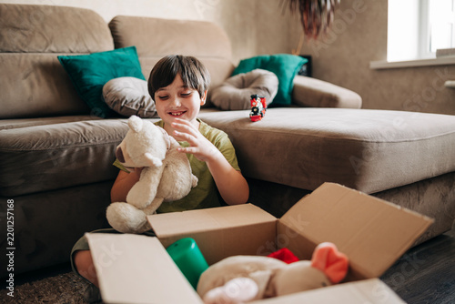 Happy cheerful kid boy packing his toys for delivery donation box. Charity and recycling