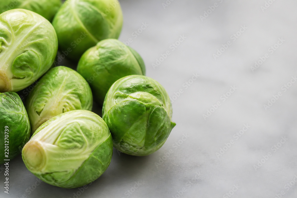Fototapeta premium Brussels sprouts are displayed on a light gray surface against a blurred background.