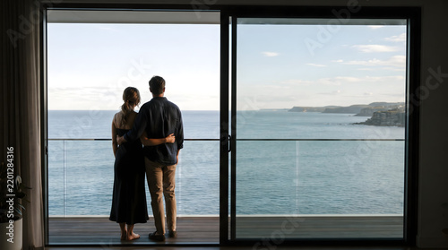 Silhouetted Couple Standing at Balcony Looking Over Ocean View