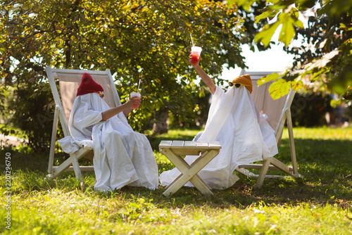two kids in Halloween ghost costumes Wearing bright hats and black glasses, they drink lemonade in the park. Halloween party
