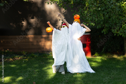 two kid in Halloween ghost costumes Wearing bright hats and black glasses,  in the park. Halloween party