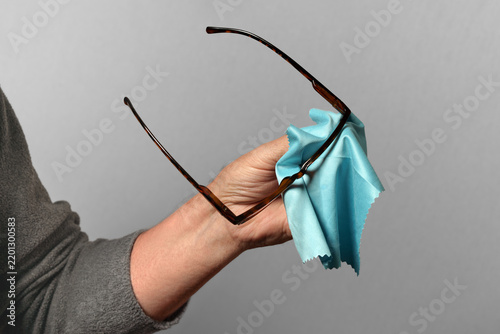 main qui nettoie les lunettes sur fond gris