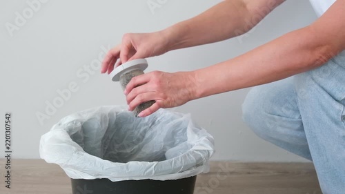 The woman is cleaning the vacuum cleaner filter of debris and dust.
