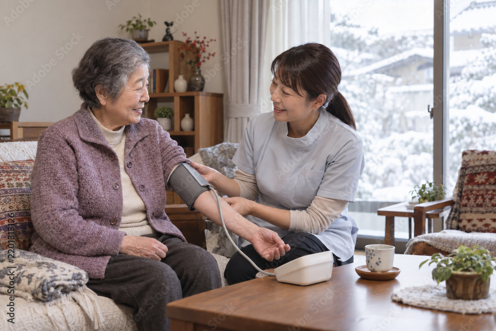 Fototapeta premium Home Care Nurse Measuring Blood Pressure of a Senior Japanese Woman in Winter 