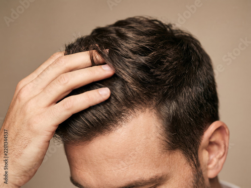 Close-up of a man's hand running through thick dark hair, illustrating healthy growth and successful hair restoration treatment.