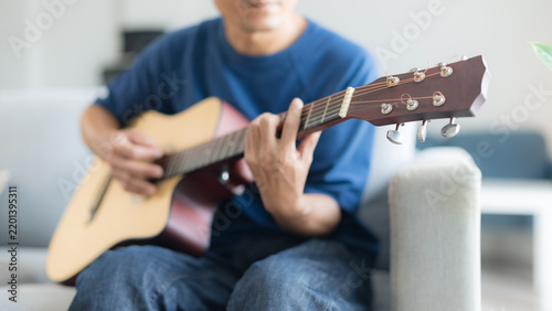 Foto A man playing an acoustic guitar while sitting comfortably on a sofa in a bright