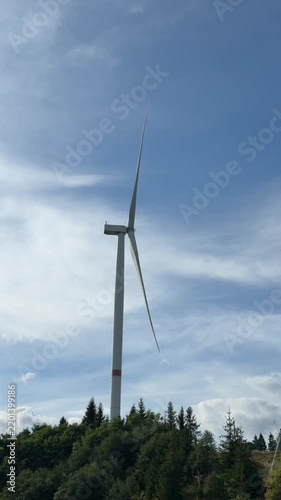 Wind Turbine Rising Above Forested Hills Under Sky
