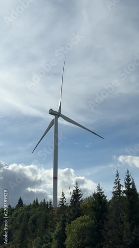 Wind Turbine Rising Above Forested Hills Under Sky