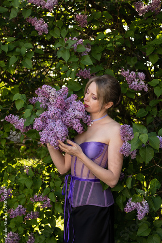 Woman surrounded by lilac blossoms creating delicate botanical aesthetic scene