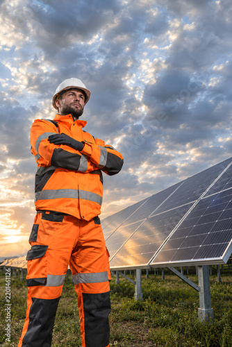 Confident solar technician portrait with dramatic sky and negative space.