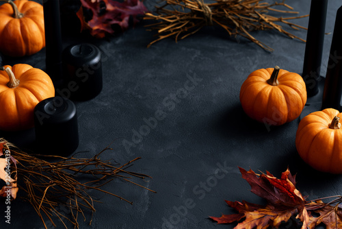 Fall decoration with pumpkins, candles, and leaves on a dark table