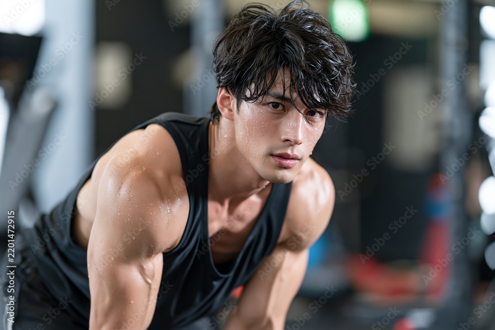 Obraz premium トレーニングジムで集中して汗を流す筋肉質な若い男性