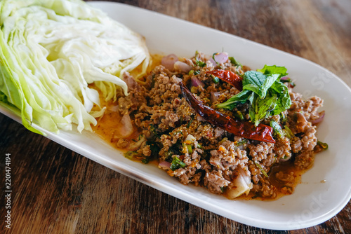 Spicy Thai beef salad with fresh herbs and cabbage, served on a white plate.