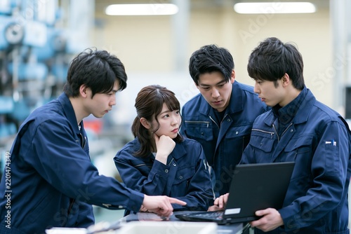 Naklejka 製造業の現場で若手社員がノートパソコンで技術を学ぶ協力的な姿