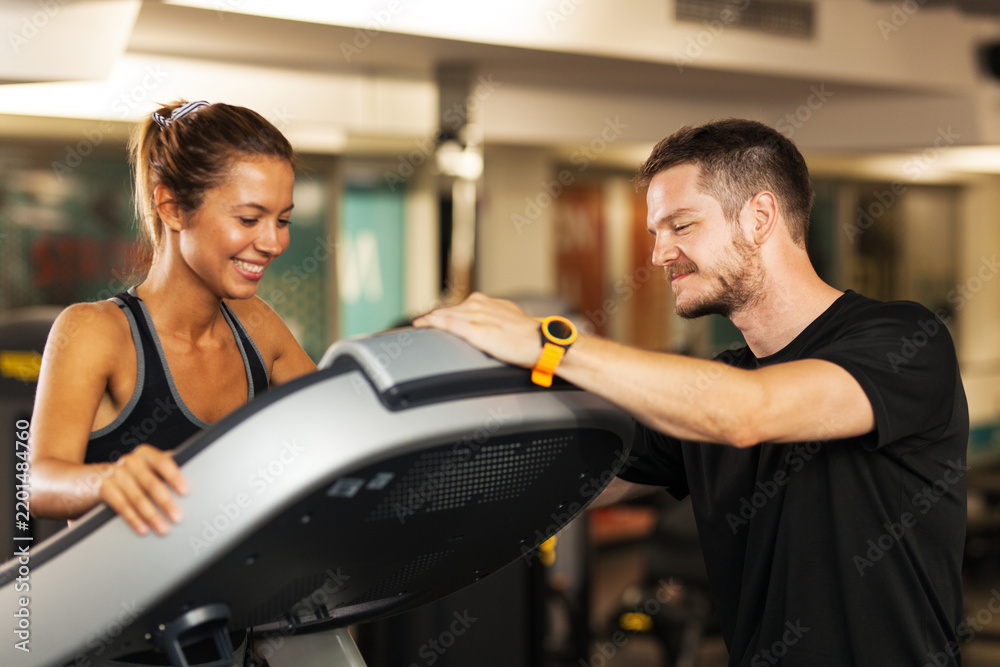 Fototapeta premium happy girl with a fitness coach walking on a treadmill