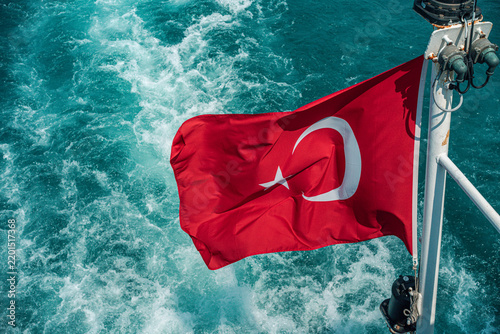 A vibrant Turkish flag flutters against the backdrop of deep turquoise waters, symbolizing national pride and maritime heritage. 