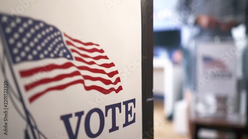 Midterm and presidential elections in USA, man voting at polling station with blurred background
