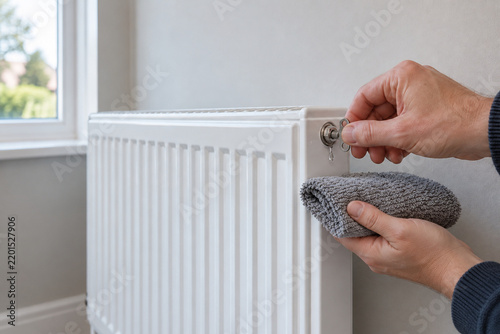 Person adjusting radiator valve with cloth in a bright room  