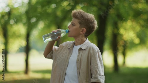 Boy Drinking Water from Plastic Bottle Outdoors in Park