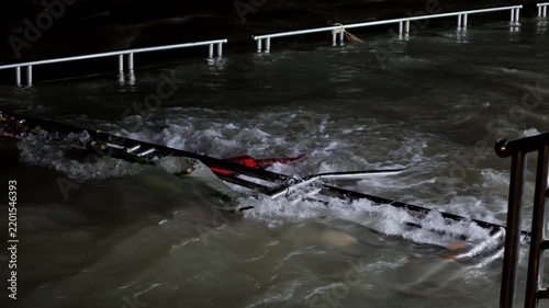 Turbulent water moves around partly submerged metal frames beside the Ganga River in Rishikesh at night.