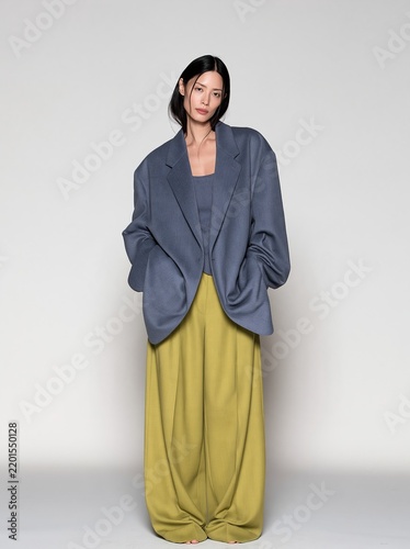 Asian woman wearing a grey blazer and bright yellow-green wide leg pants, posing with a confident look for fashion lookbooks and apparel ads