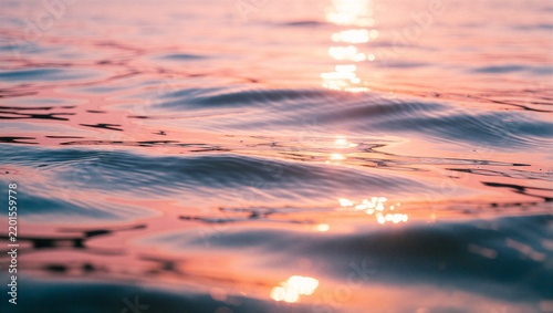 Close-up of rippling sea water reflecting a pink sunset