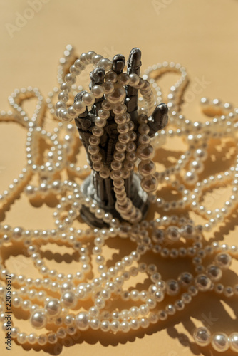 Robotic Hand Wrapped in Pearl Beads on Golden Background, Futuristic Luxury Concept