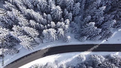 Aerial view of car driving on winter forest road