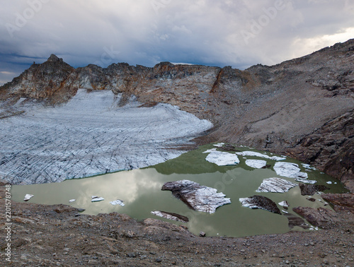 Melting glacier with water pool located in a rocky mountain area, Austria