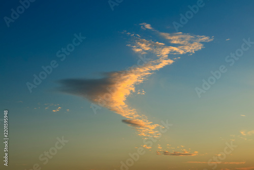 Golden sunset clouds floating in blue sky at dusk 
