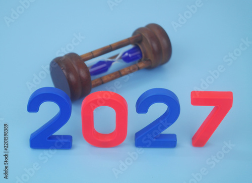 Foto Numbers 2027 and hourglass on blue background.