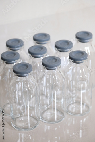 Close-up of empty clear glass bottles with grey rubber caps